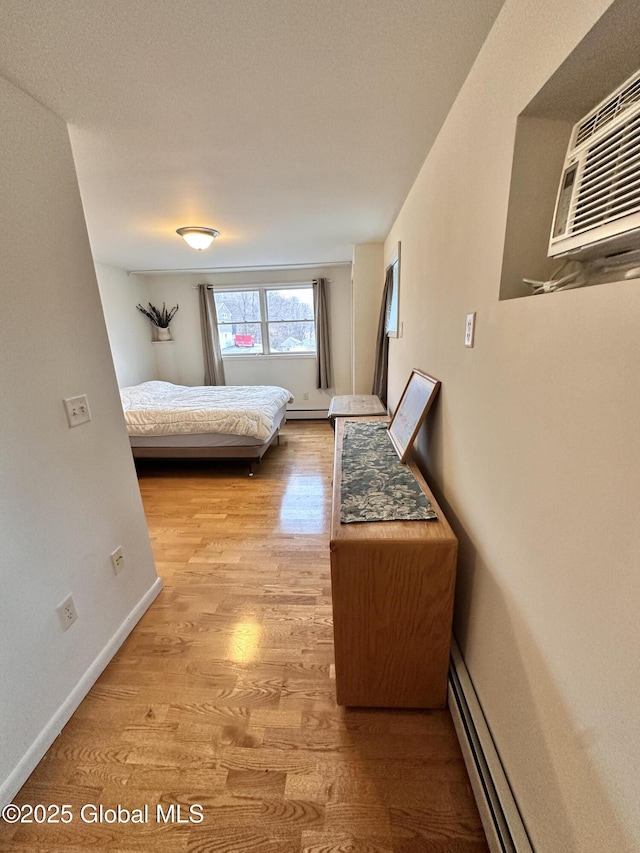 bedroom featuring light wood-style floors, baseboards, and baseboard heating