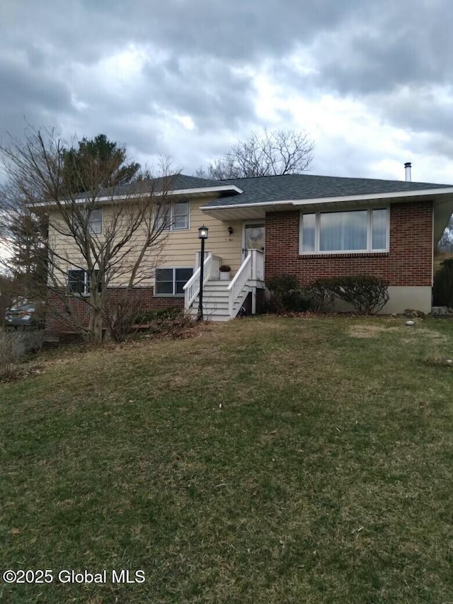 view of front of property with brick siding, a front lawn, and entry steps