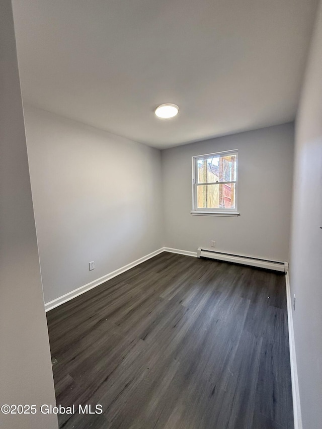 unfurnished room featuring a baseboard heating unit, dark wood-style floors, and baseboards