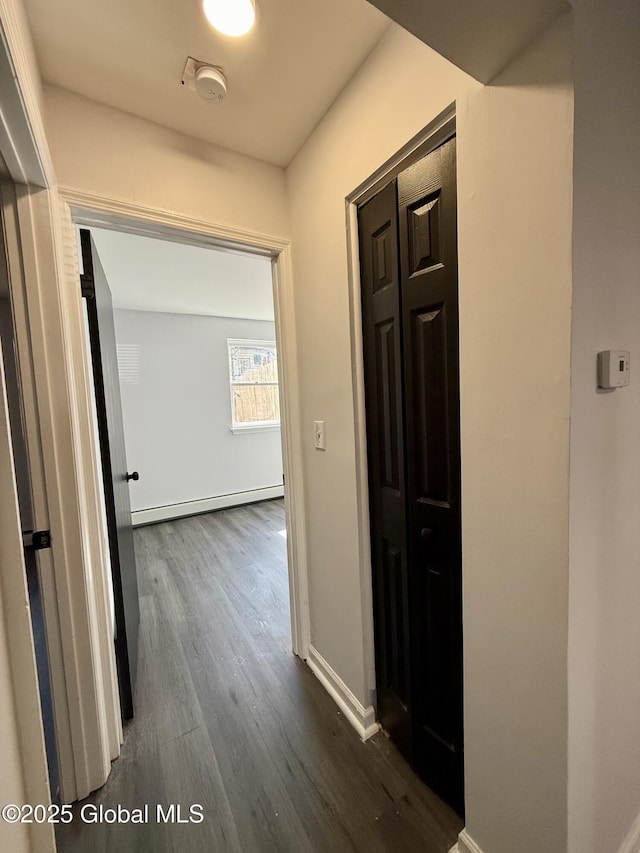 hall with a baseboard heating unit, dark wood finished floors, and baseboards