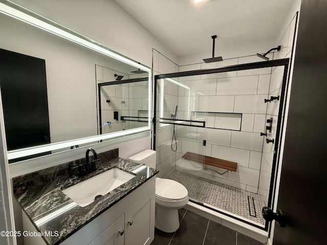 bathroom featuring tile patterned floors, toilet, a shower stall, and vanity