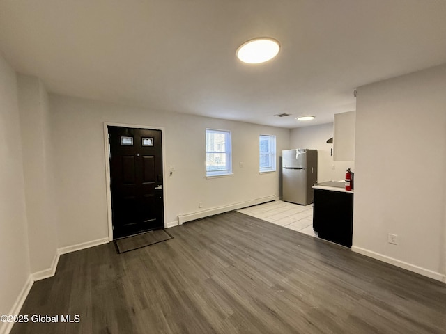 kitchen featuring light wood-style flooring, freestanding refrigerator, light countertops, baseboards, and baseboard heating