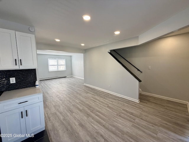 unfurnished living room with baseboards, stairs, recessed lighting, light wood-style flooring, and a baseboard radiator