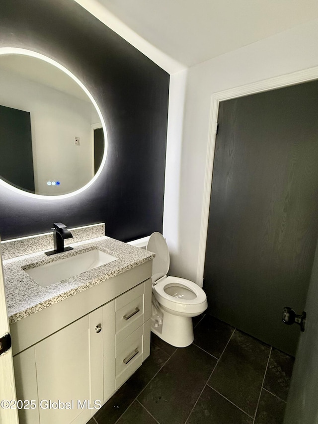 half bath featuring toilet, vanity, and tile patterned flooring