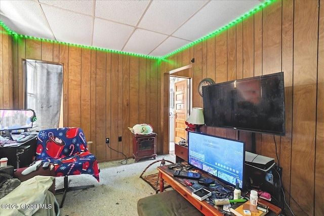 living area with wood walls, a paneled ceiling, and carpet