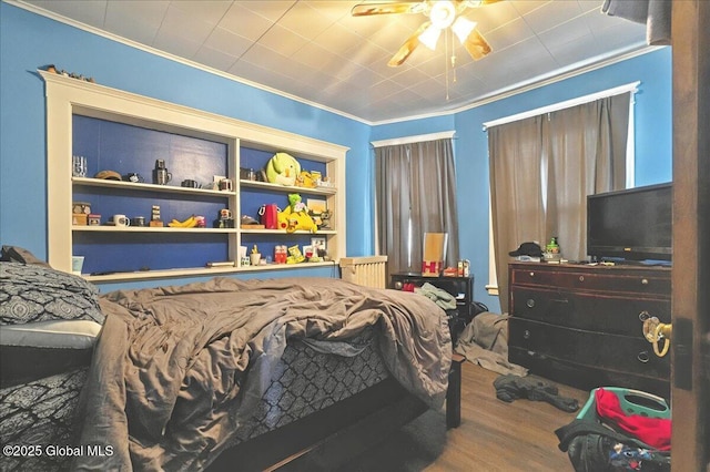 bedroom with crown molding, radiator heating unit, and wood finished floors