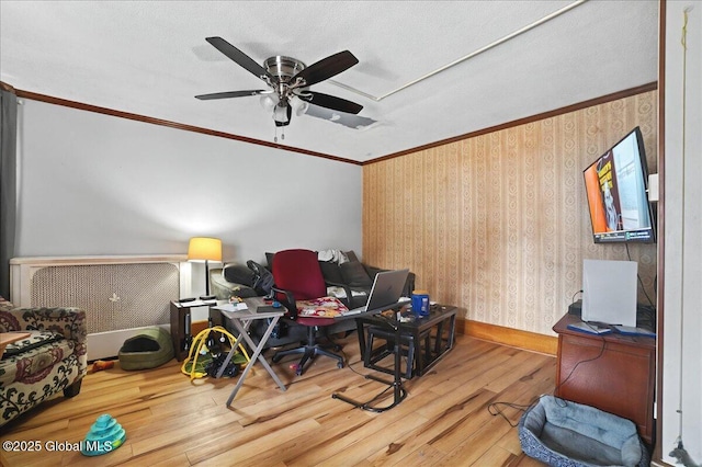 sitting room with wallpapered walls, crown molding, baseboards, ceiling fan, and wood finished floors