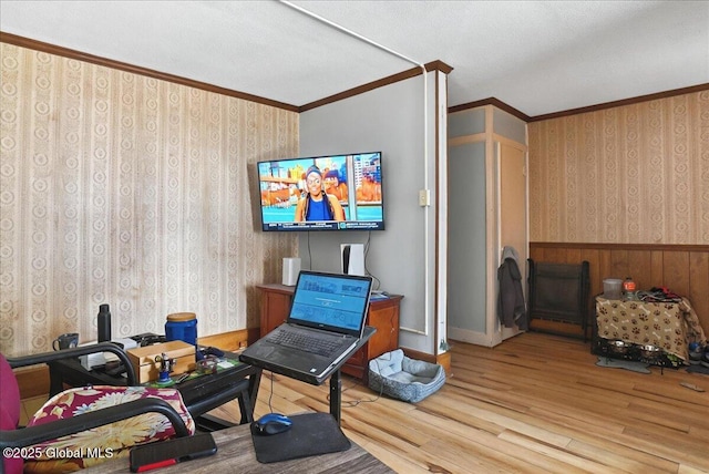 office area with a wainscoted wall, wood finished floors, crown molding, and wallpapered walls