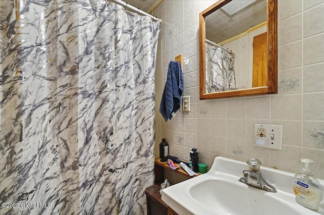 bathroom featuring tile walls, a shower with curtain, and a sink