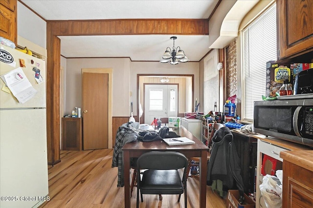 office area featuring a notable chandelier, light wood-style flooring, wooden walls, and crown molding