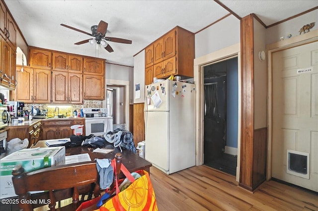 kitchen featuring brown cabinets, light wood-type flooring, freestanding refrigerator, and a ceiling fan