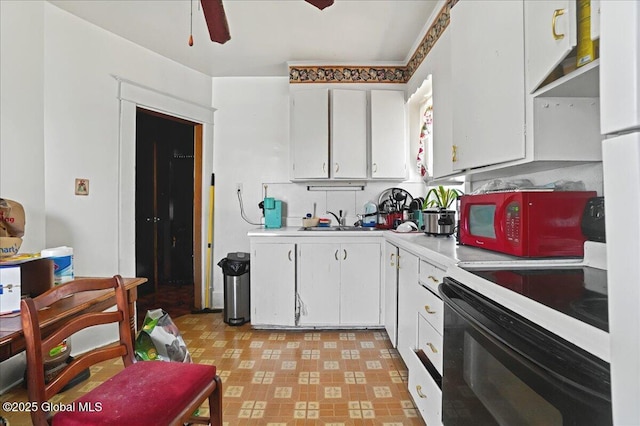 kitchen with white cabinetry, light countertops, white microwave, and black electric range oven