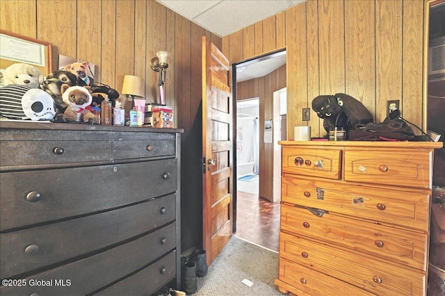 bedroom with carpet flooring and wood walls