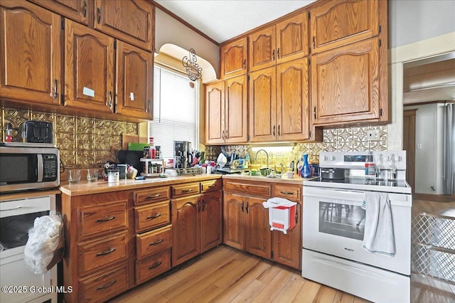 kitchen with stainless steel microwave, light countertops, decorative backsplash, white electric range oven, and a sink