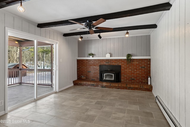 unfurnished living room with beam ceiling, a ceiling fan, wooden walls, baseboard heating, and a wood stove