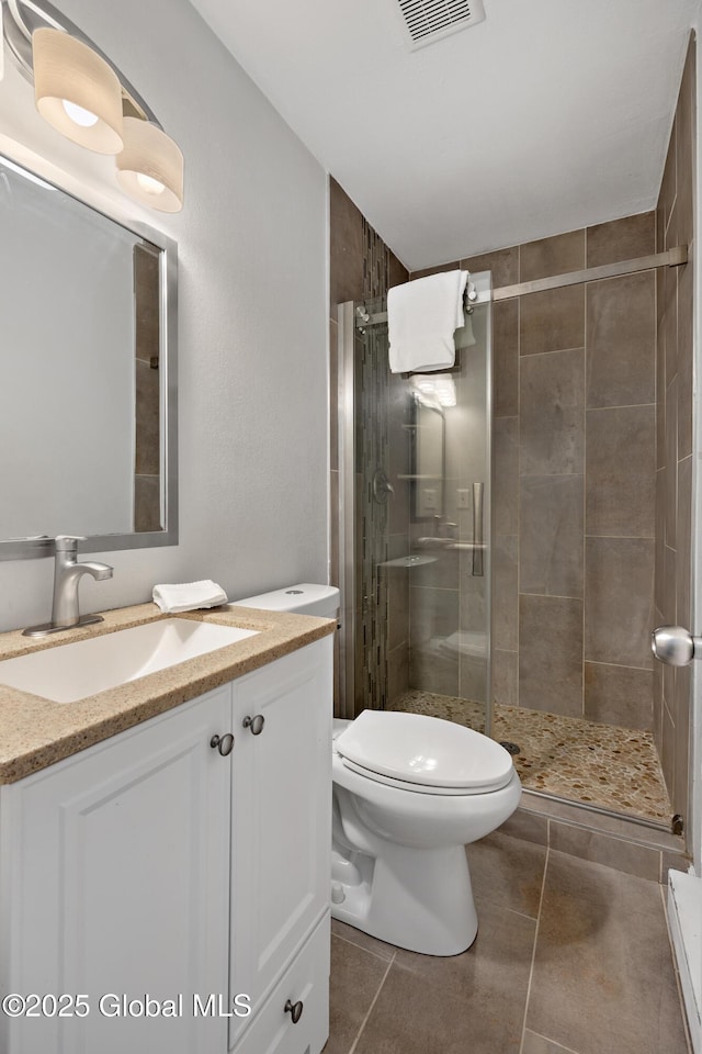 bathroom featuring tile patterned flooring, visible vents, a shower stall, toilet, and vanity