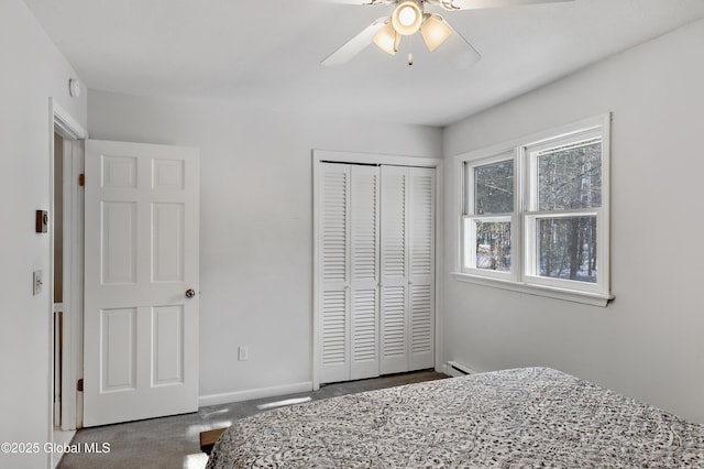 carpeted bedroom with a closet, baseboard heating, a ceiling fan, and baseboards