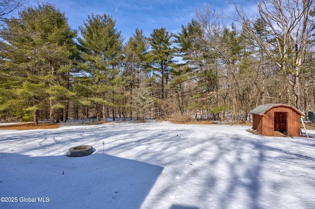 snowy yard featuring a storage shed and an outdoor structure