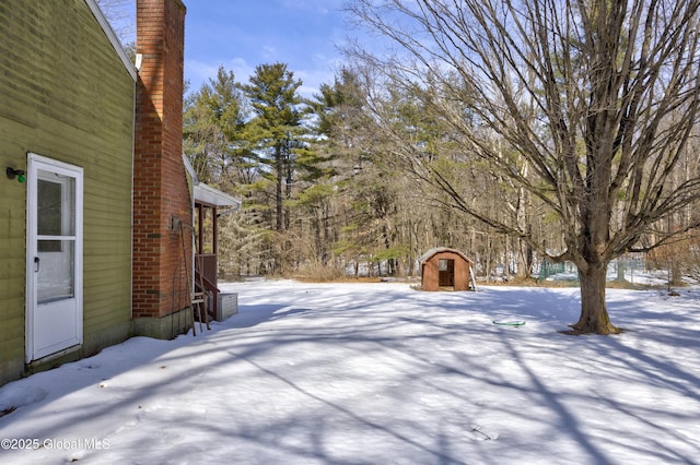 yard layered in snow with a storage shed and an outdoor structure