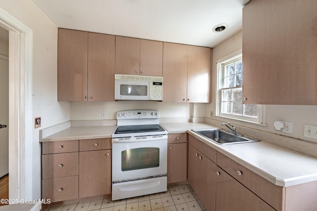 kitchen featuring light floors, white appliances, light countertops, and a sink