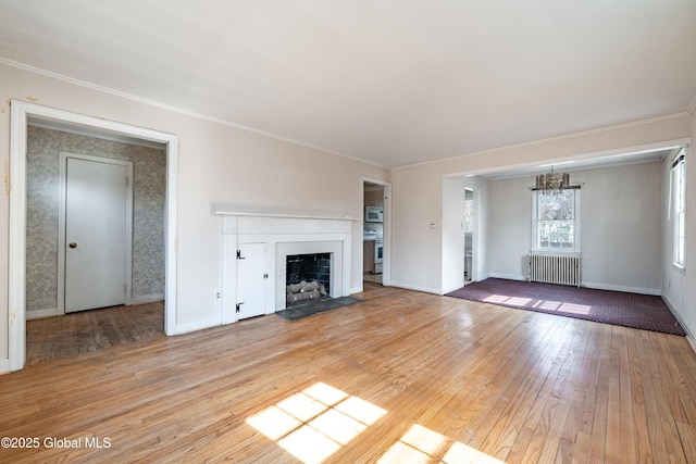 unfurnished living room featuring baseboards, light wood-style flooring, radiator heating unit, a fireplace with flush hearth, and crown molding