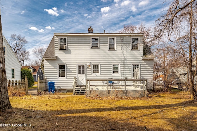 back of property featuring a shingled roof, a yard, fence, and a chimney