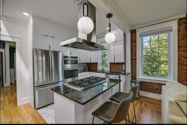 kitchen featuring brick wall, a sink, stainless steel appliances, white cabinetry, and a center island