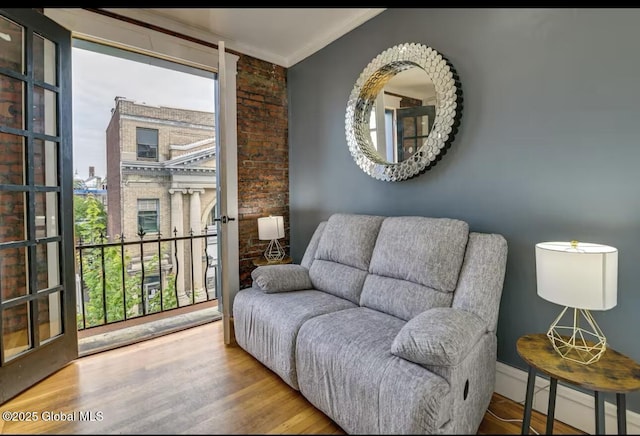 sitting room featuring ornamental molding, a fireplace, a baseboard heating unit, and wood finished floors