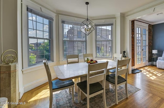 dining room with plenty of natural light, a notable chandelier, wood finished floors, and crown molding