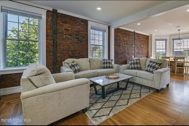 living room with wood finished floors, brick wall, and ornamental molding