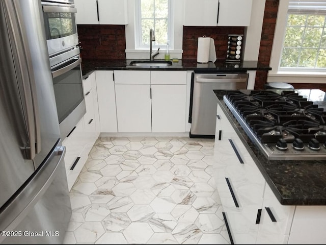 kitchen featuring a healthy amount of sunlight, appliances with stainless steel finishes, white cabinetry, and a sink