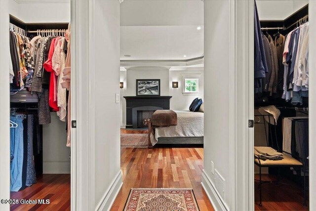 spacious closet with a fireplace and wood finished floors