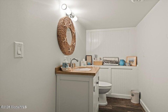 bathroom with toilet, vanity, and wood finished floors