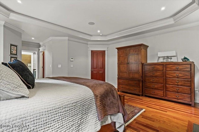 bedroom featuring a tray ceiling, light wood-style flooring, recessed lighting, and a closet