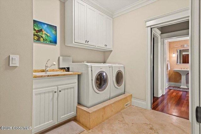 washroom featuring baseboards, cabinet space, ornamental molding, a sink, and washer and dryer