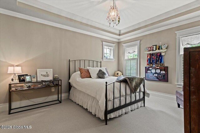 carpeted bedroom with a tray ceiling, baseboards, an inviting chandelier, and ornamental molding