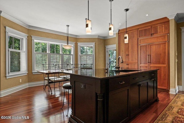 kitchen with dark countertops, crown molding, dark wood-type flooring, and a sink