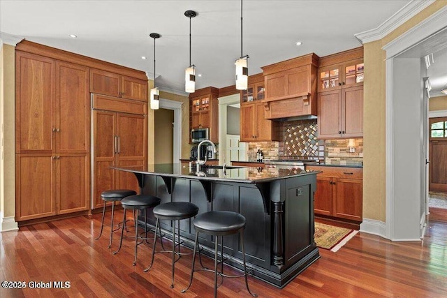 kitchen with a sink, dark countertops, brown cabinetry, and paneled refrigerator