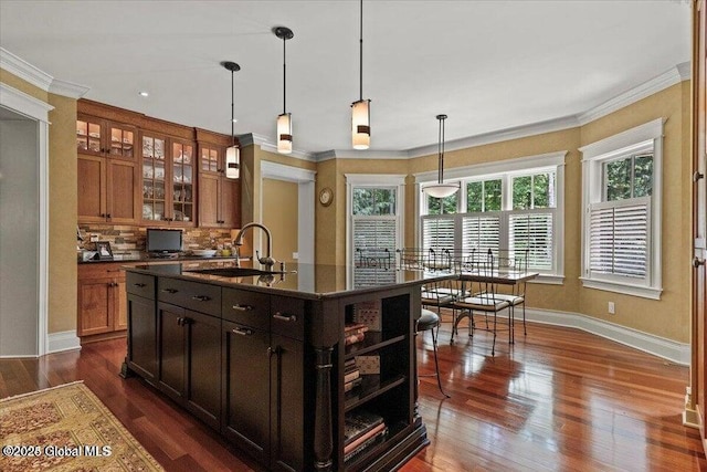 kitchen featuring dark countertops, ornamental molding, dark wood-style flooring, and a sink