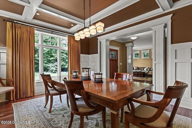 dining space featuring ornamental molding, decorative columns, wood finished floors, a decorative wall, and coffered ceiling