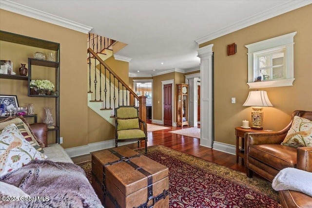 living area with ornamental molding, wood finished floors, baseboards, stairs, and ornate columns