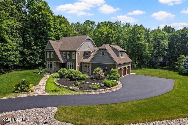 shingle-style home featuring a front lawn, an attached garage, and driveway