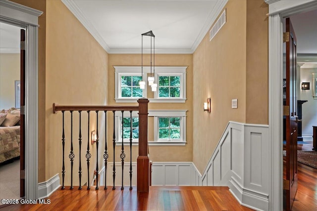 staircase with wood finished floors, visible vents, and wainscoting