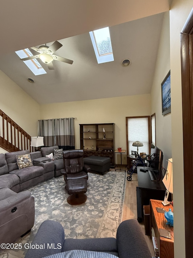 living area with visible vents, a skylight, a ceiling fan, and wood finished floors