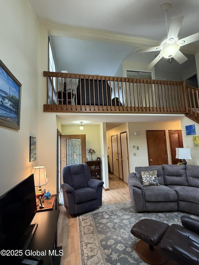 living room with a high ceiling, a ceiling fan, and wood finished floors