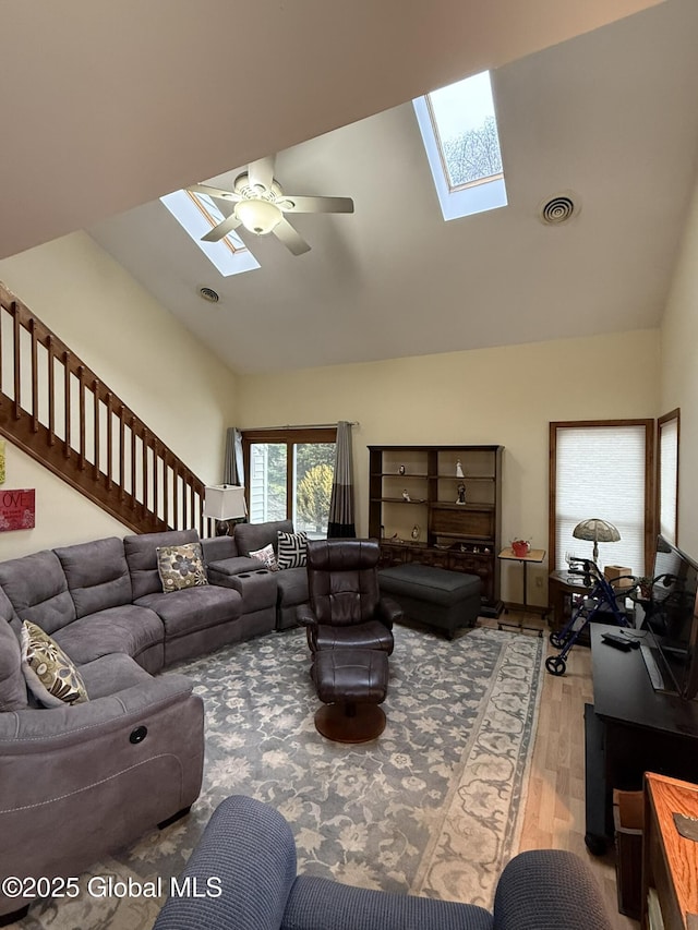 living area with a skylight, wood finished floors, visible vents, and ceiling fan