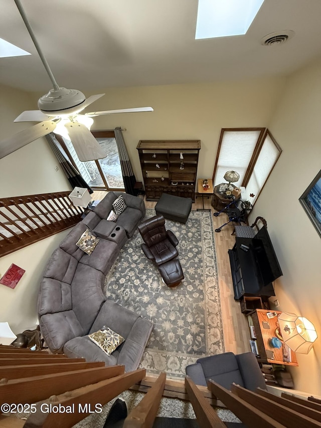 living room featuring visible vents, wood finished floors, a skylight, and a ceiling fan