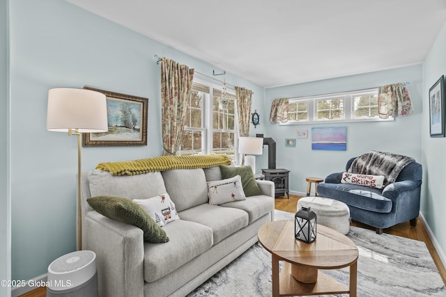 living room with baseboards, wood finished floors, and a wood stove