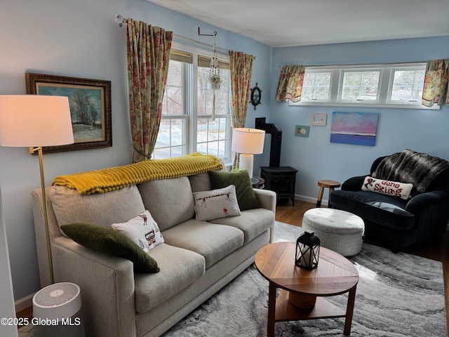 living room with a healthy amount of sunlight, a wood stove, baseboards, and wood finished floors