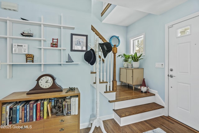 foyer featuring baseboards, wood finished floors, and stairs